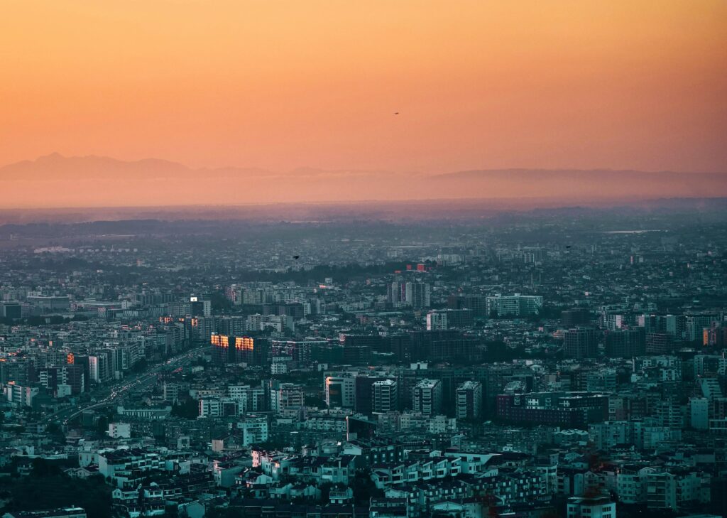 A stunning aerial shot of Tirana, Albania with vibrant orange skies during sunset. Perfect for travel and cityscape enthusiasts.